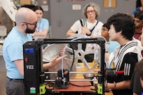 Ryan Fisher, an engineer in the Additive Manufacturing Branch at Naval Surface Warfare Center Carderock Division, shows students 3D printed materials in Carderock’s Additive Manufacturing Lab during a tour for the Carderock Math Contest on Friday, April 4, 2025, in West Bethesda, Maryland.