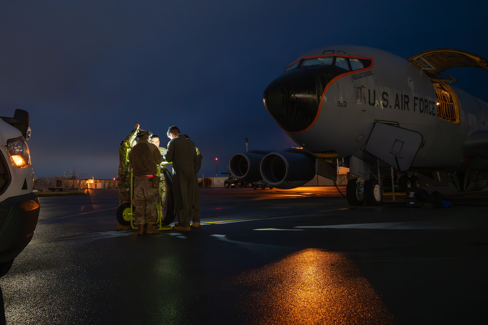 military members stand on a flightline in front of an aircraft called a KC-135 Stratotanker reviewing maintenance records.