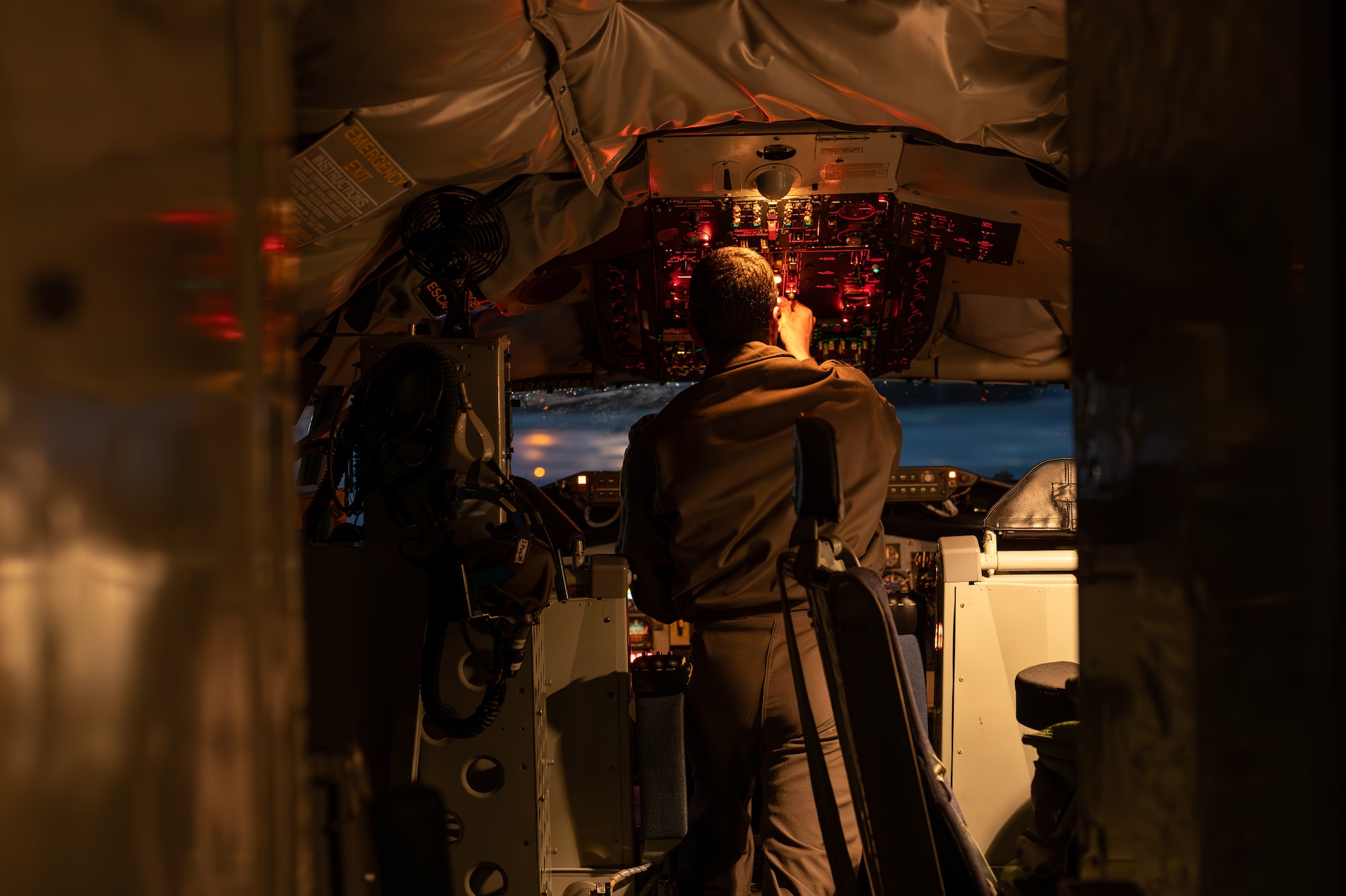 A military member touches dials inside of a cockpit before a flight