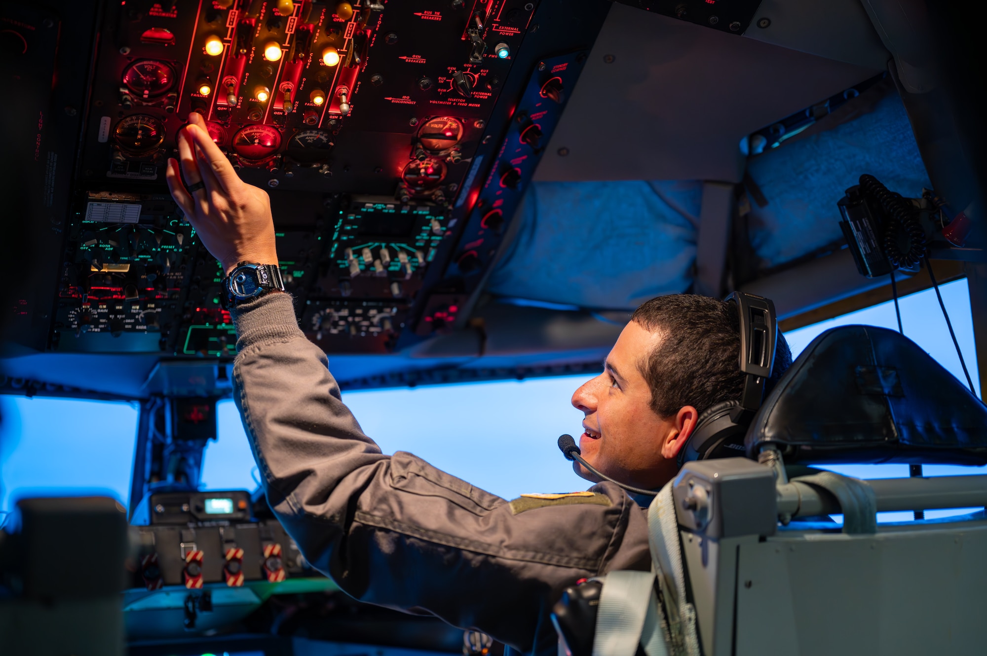 A military member sits in a pilots seat touching dials before a take off
