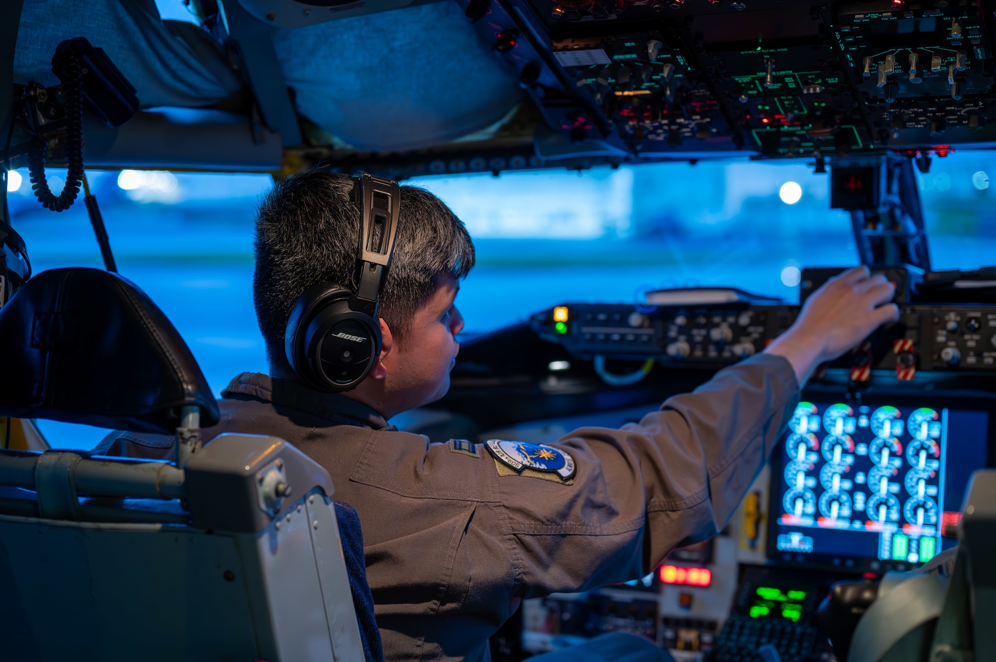 A military member sits in a pilots seat touching dials before a take off