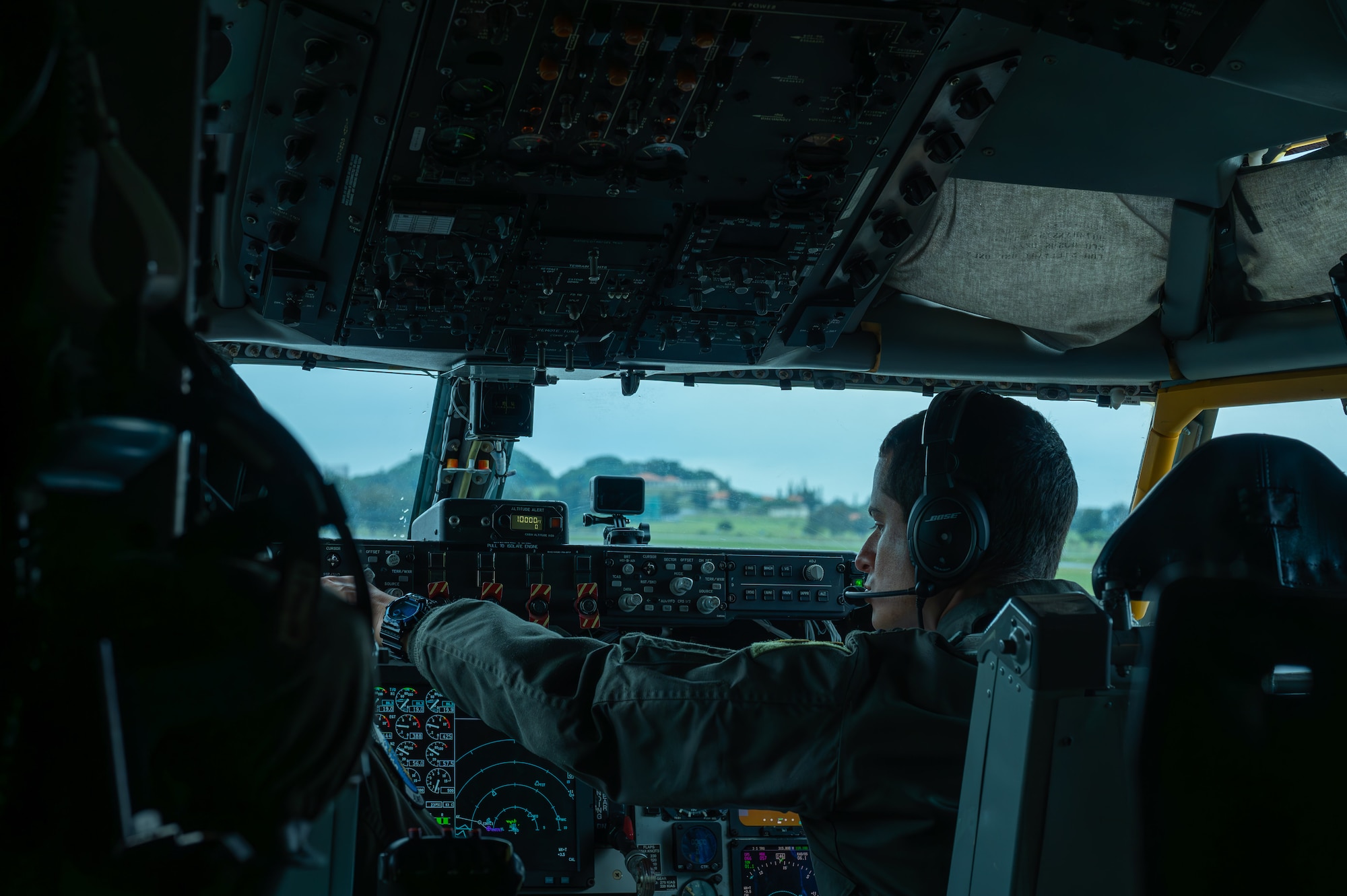 A military member sits in a pilots seat preparing to take off