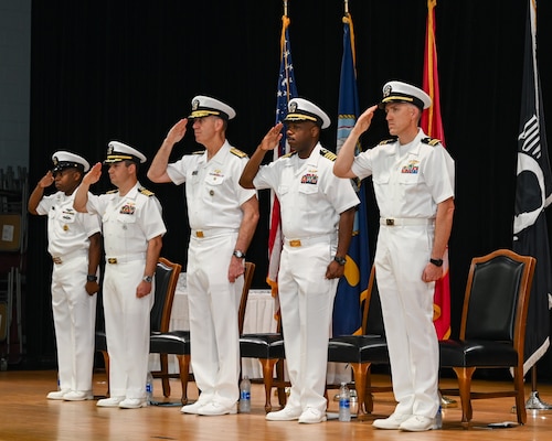 U.S. Navy Capt. Tim Campbell, center left, outgoing commander of Task Force (CTF) 57, U.S. Navy Vice Adm. George Wikoff, center, commander of U.S. Naval Forces Central Command and U.S. 5th Fleet, and U.S. Navy Capt. Dennis Jensen, center right, incoming commander of CTF 57, render honors during a change-of-command ceremony in Manama, Bahrain