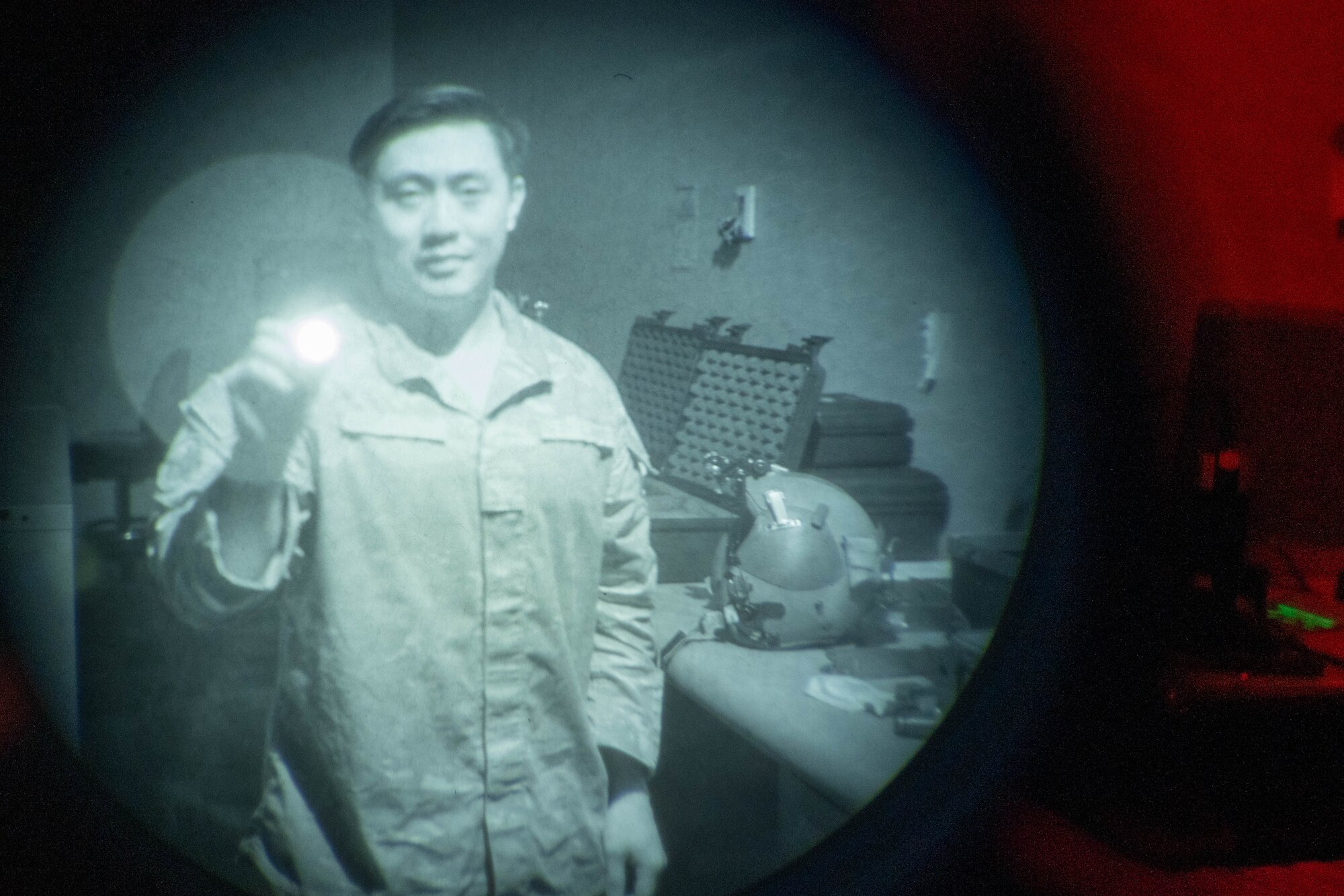 A man holds an ultraviolet glow stick in front of night vision goggles
