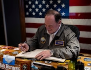 The Secretary of the Navy, the Hon. John C. Phelan, signs the ship's guest book in the in-port cabin of the world’s largest aircraft carrier, USS Gerald R. Ford (CVN 78), April 11, 2025.