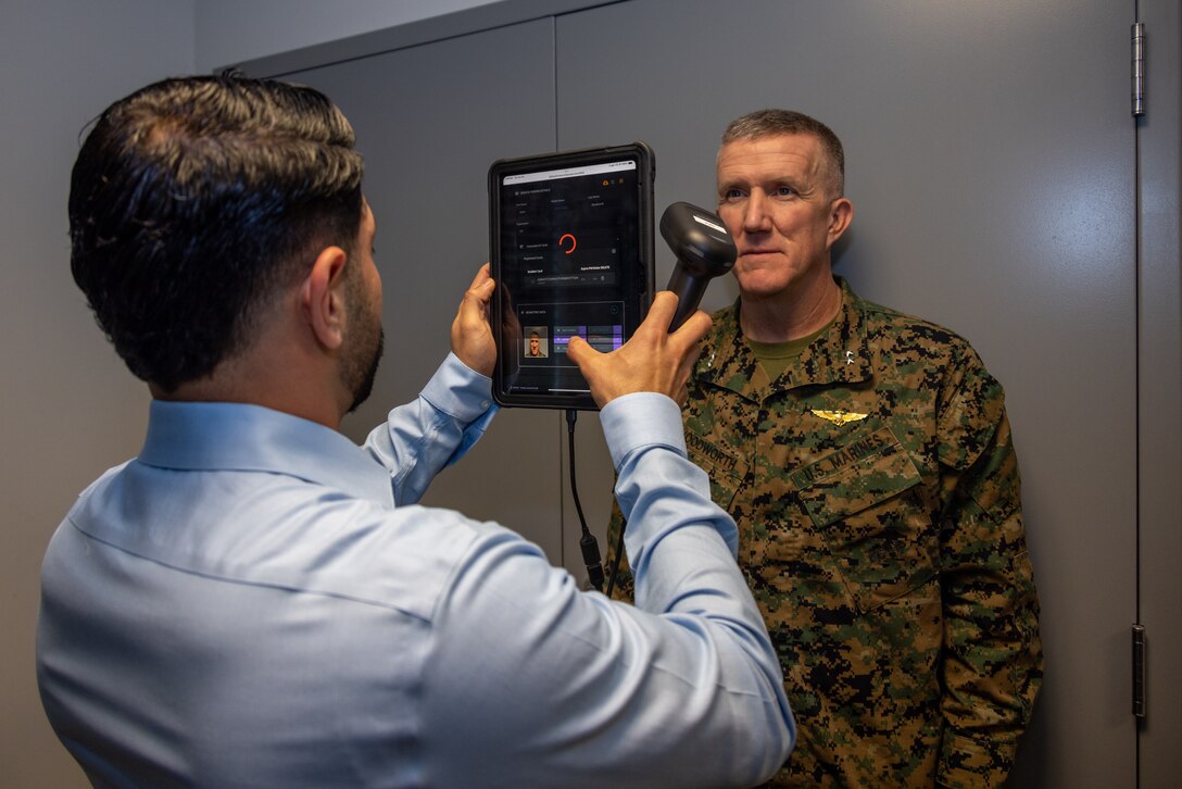Jose Rivera-Smith, an assistant services officer for the Provost Marshal’s Office, Marine Corps Air Station Miramar, registers U.S. Marine Corps Maj. Gen. Jason Woodworth, the commanding general for Marine Corps Installations Command, for a biometric facial recognition system at MCAS Miramar, California, Jan. 29, 2025. MCAS Miramar will begin utilizing Idemia biometric facial recognition system at the East Gate which will allow registered users to access the installation in a more efficient manner. Woodworth toured the installation, speaking on various innovations occurring on MCAS Miramar. (U.S Marine Corps Photo by Lance Cpl. Jackson Rush)