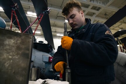Aviation Structural Mechanic 3rd Class Shea Fortin, assigned to the “Tridents” of Helicopter Sea Combat Squadron (HSC) 9, disassembles the housing of a pylon lock pin on an MH-60S Sea Hawk during routine maintenance in the hangar bay of the world's largest aircraft carrier, USS Gerald R. Ford (CVN 78), March 18, 2025.
