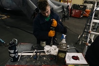 Aviation Structural Mechanic 3rd Class Shea Fortin, assigned to the “Tridents” of Helicopter Sea Combat Squadron (HSC) 9, disassembles the housing of a pylon lock pin on an MH-60S Sea Hawk during routine maintenance in the hangar bay of the world's largest aircraft carrier, USS Gerald R. Ford (CVN 78), March 18, 2025.