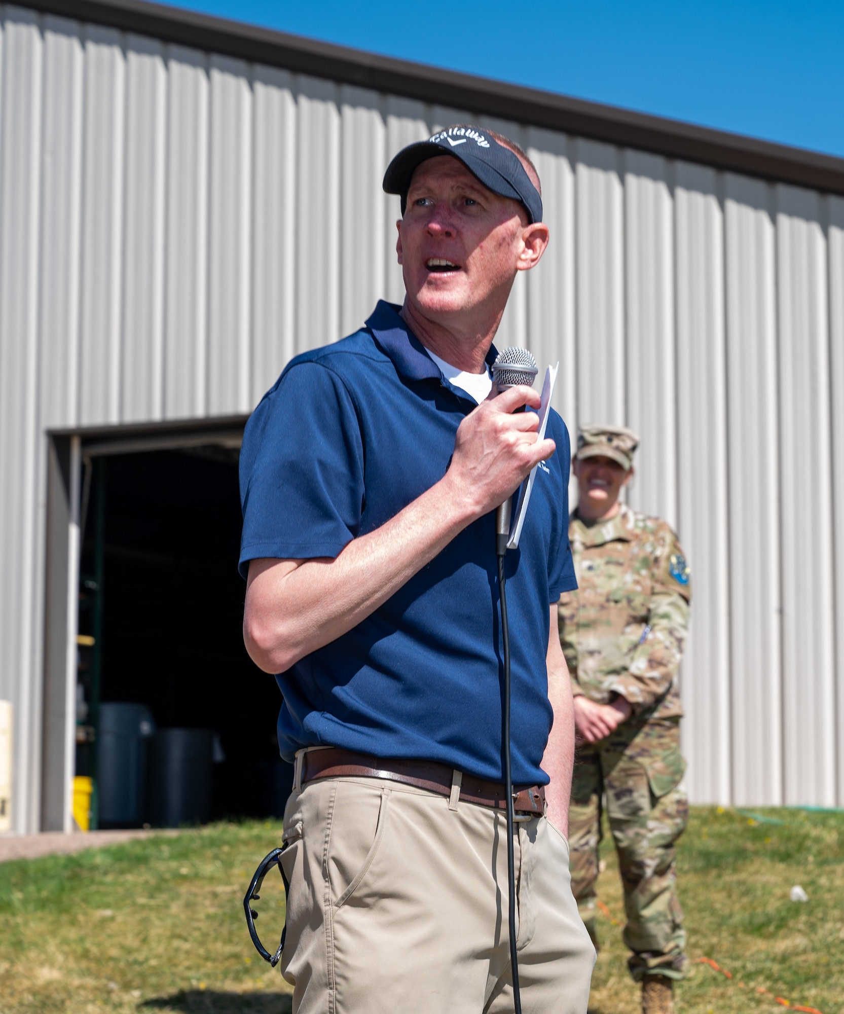 A man stands on a hill with a microphone.