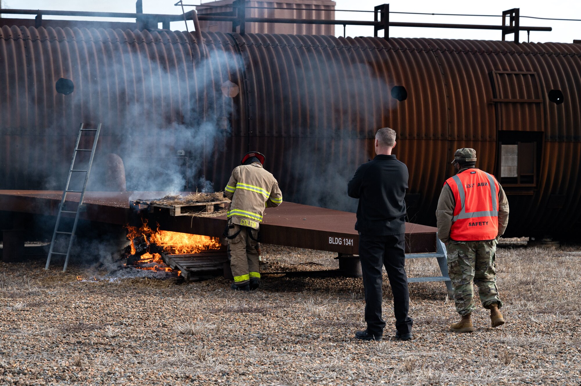 Exercise leadership monitor a firefighter starting a controlled fire.