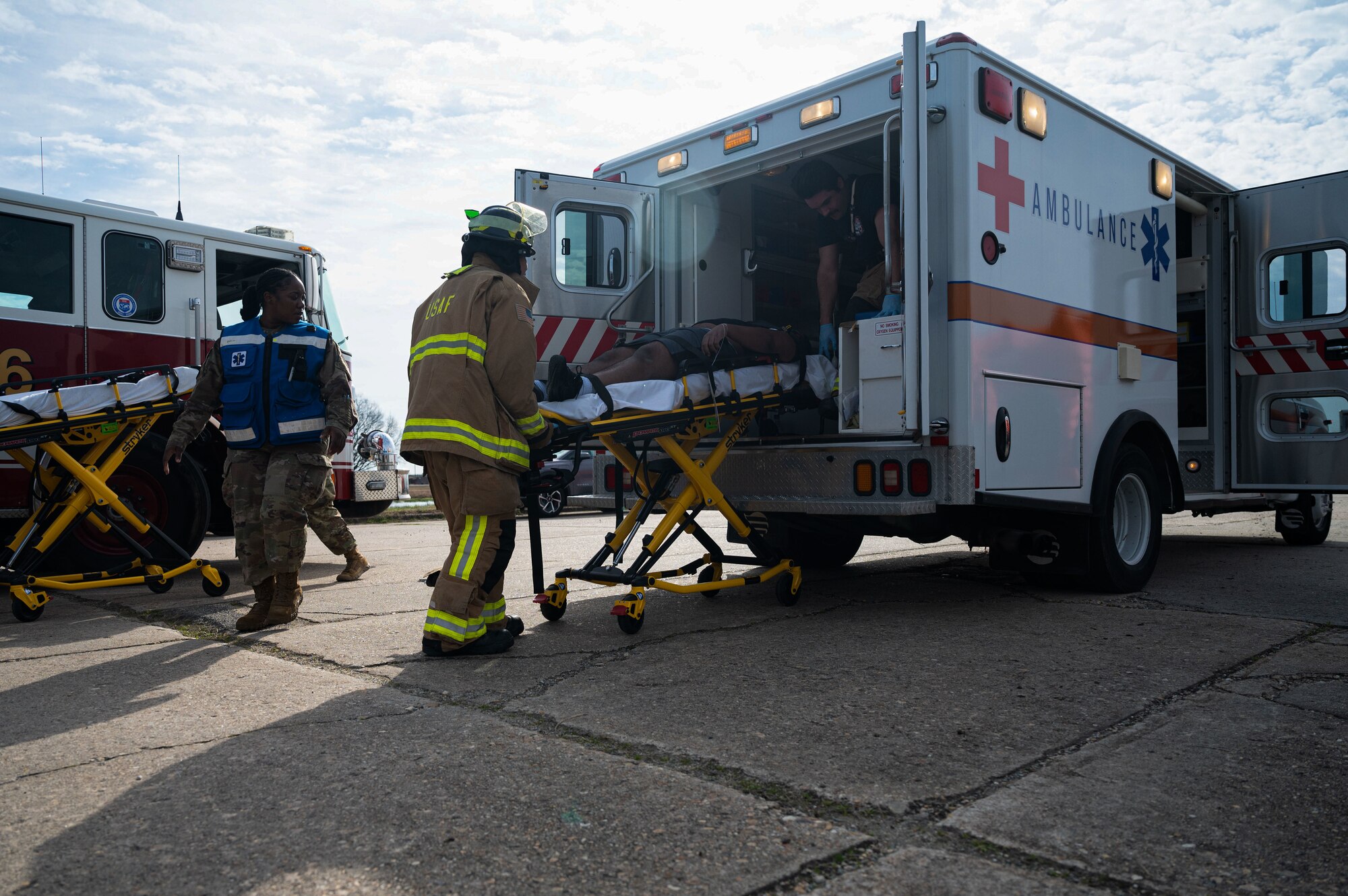 Emergency responders place a patient in the back of an ambulance during a base exercise.