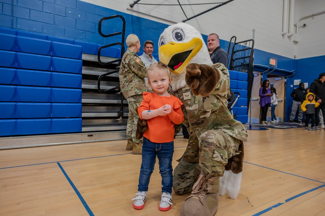 JB the Eagle, Joint Base Langley-Eustis’ mascot power points at the camera while taking a photo with a local child