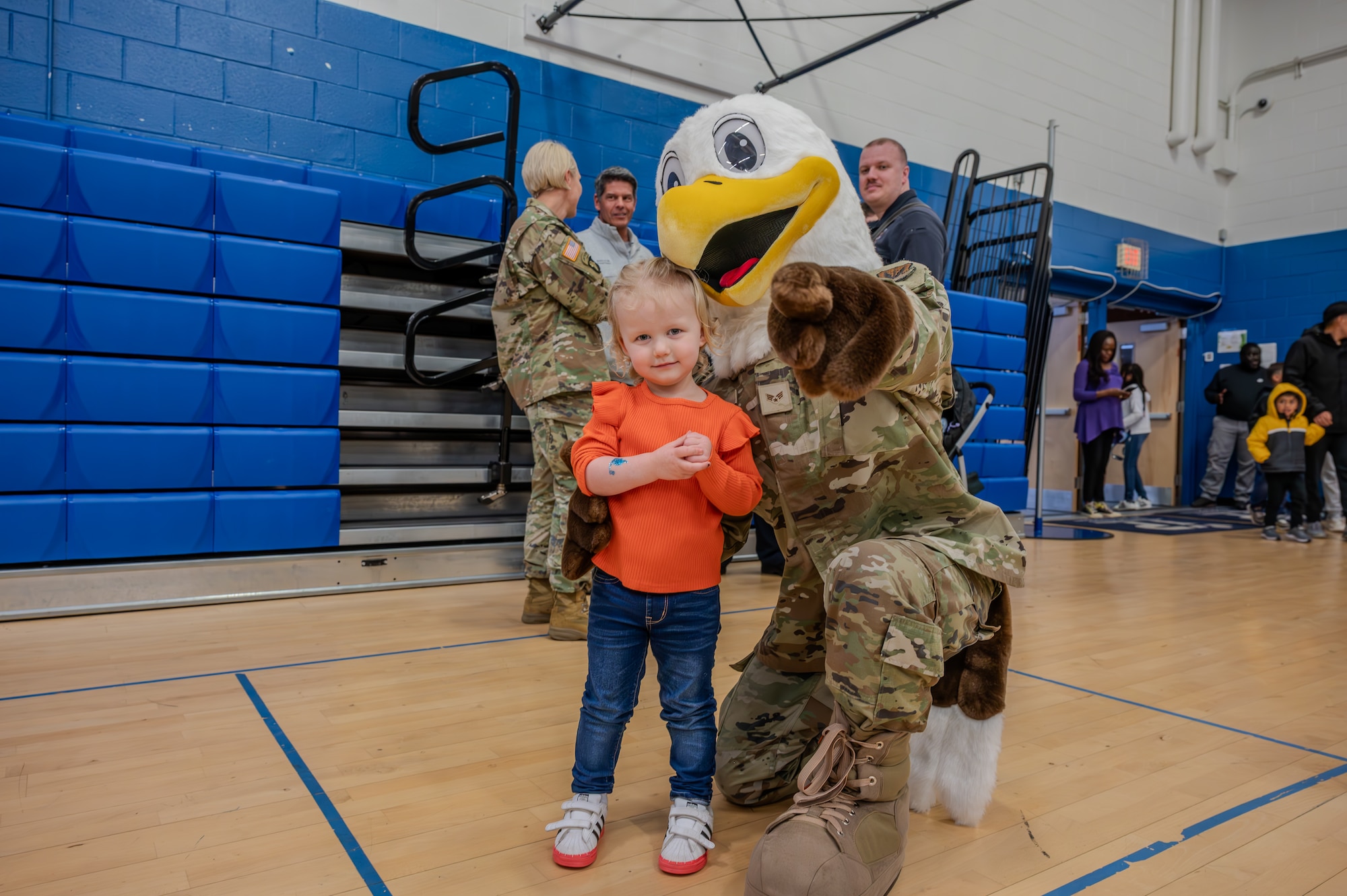 JB the Eagle, Joint Base Langley-Eustis’ mascot power points at the camera while taking a photo with a local child