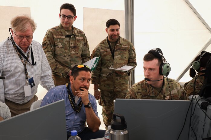 Tech. Sgt. Peyton Shaffer, right, a weapons director for 752 Operations Support Squadron, discusses his observations of a mission thread on the Tactical Operation Center – Light with members of the Air Force Operational Test and Evaluation Center, the 605th Test and Evaluations Squadron, and the 46th Test Squadron during Project Convergence Capstone 5 at the National Training Center, Fort Irwin, California, March 10, 2025. PC-C5 provides an experimental, operational venue for the Air Force and joint forces to test new and emerging technologies. (Official Air Force Photo by Morgan Brown).