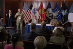 Army Lt. Gen. Mark Simerly speaks to a room of seated participants with other DLA senior leaders at a table behind him