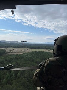 Soldiers from Knoxville’s 1-230th Assault Helicopter Battalion prepare to drop water from a Helicopter Bucket to combat a wildfire near Turtletown, in Polk County, April 15.