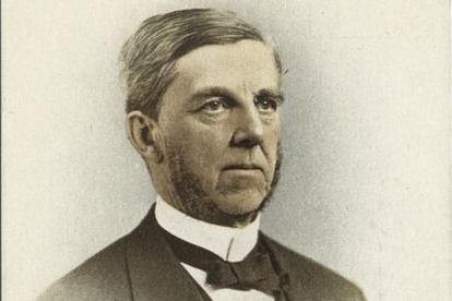 A portrait shows a man in a suit and bowtie looking to the right.