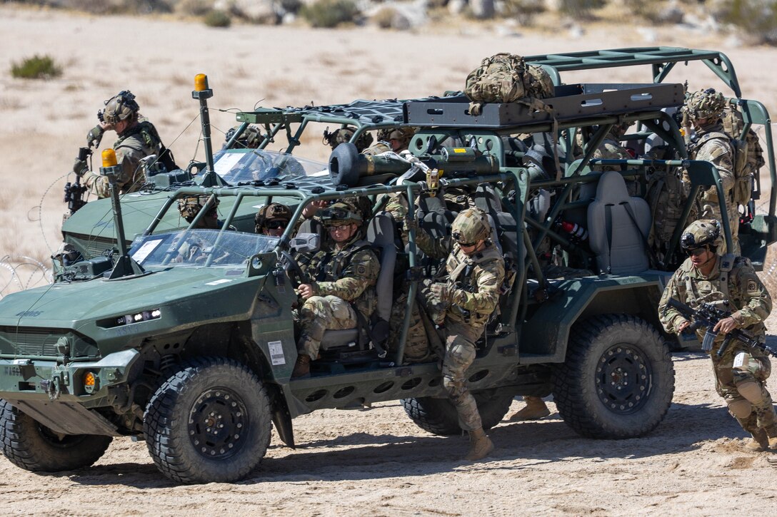 Soldiers depart loaded two occupied military vehicles in the desert.