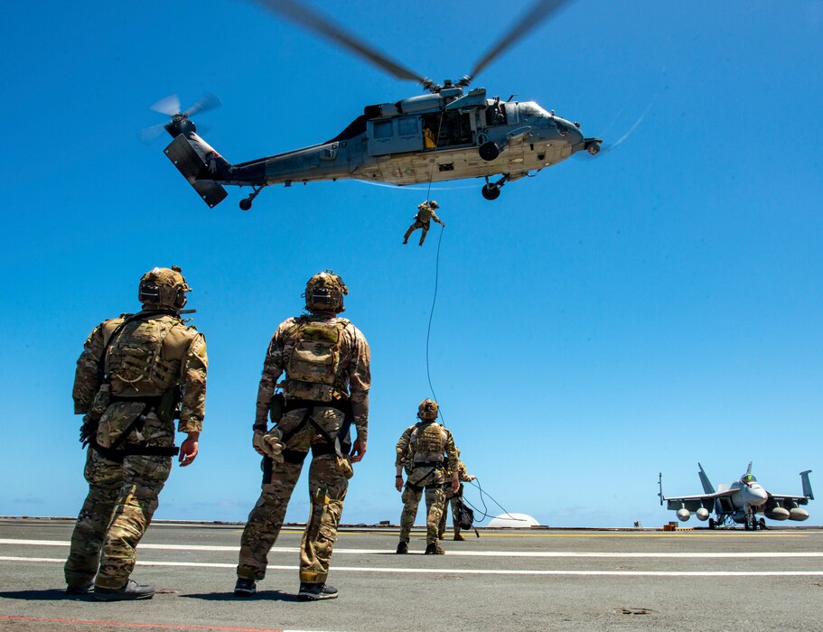 Members of Explosive Ordnance Disposal Mobile Unit 11 repel out of an MH-60S Sea Hawk helicopter from the “Indians” of Helicopter Sea Combat Squadron (HSC) 6 onto the flight deck of the aircraft carrier USS Nimitz (CVN 68) in the Pacific Ocean, April 13, 2025.