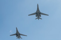 The undersides of two gray aircraft appear in a blue sky background.