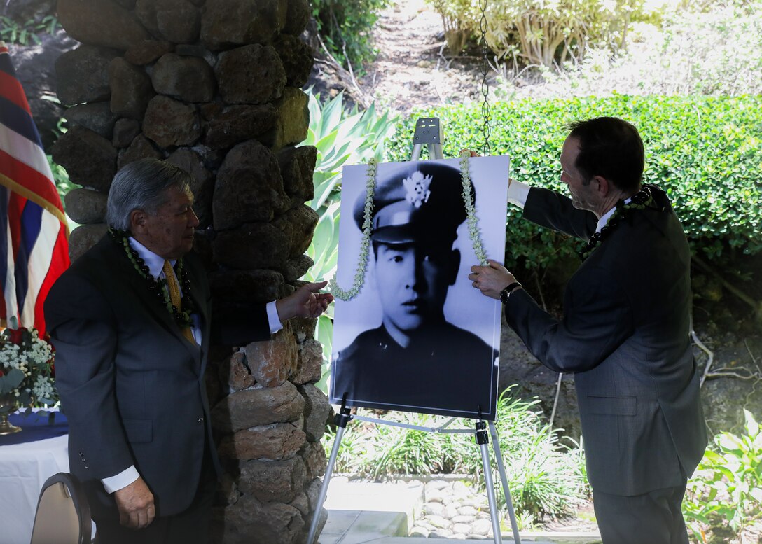 From Right to left, Dr. Michael Latham, 17th president of Punahou School, and Dr. Robert M. Wai Jr., nephew of Capt. Francis Brown Wai, place lei around Wai’s photo in honor of his legacy during the Congressional Medal of Honor ceremony at Punahou School, April 14, 2025.