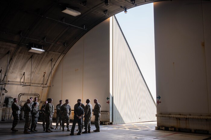 A group of people stand in a hangar.