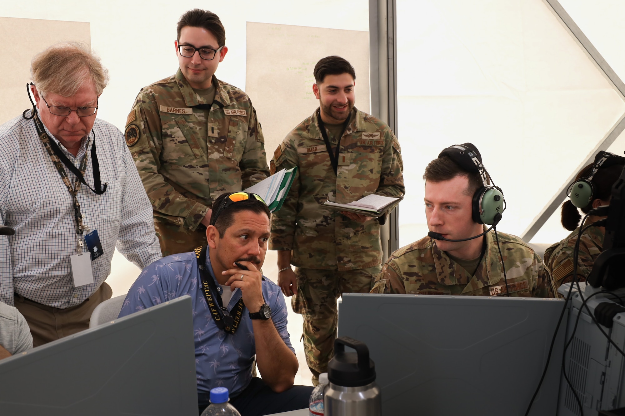 Tech. Sgt. Peyton Shaffer, right, a weapons director for 752 Operations Support Squadron, discusses his observations of a mission thread on the Tactical Operation Center – Light with members of the Air Force Operational Test and Evaluation Center, the 605th Test and Evaluations Squadron, and the 46th Test Squadron during Project Convergence Capstone 5 at the National Training Center, Fort Irwin, California, March 10, 2025. PC-C5 provides an experimental, operational venue for the Air Force and joint forces to test new and emerging technologies. (Official Air Force Photo by Morgan Brown).