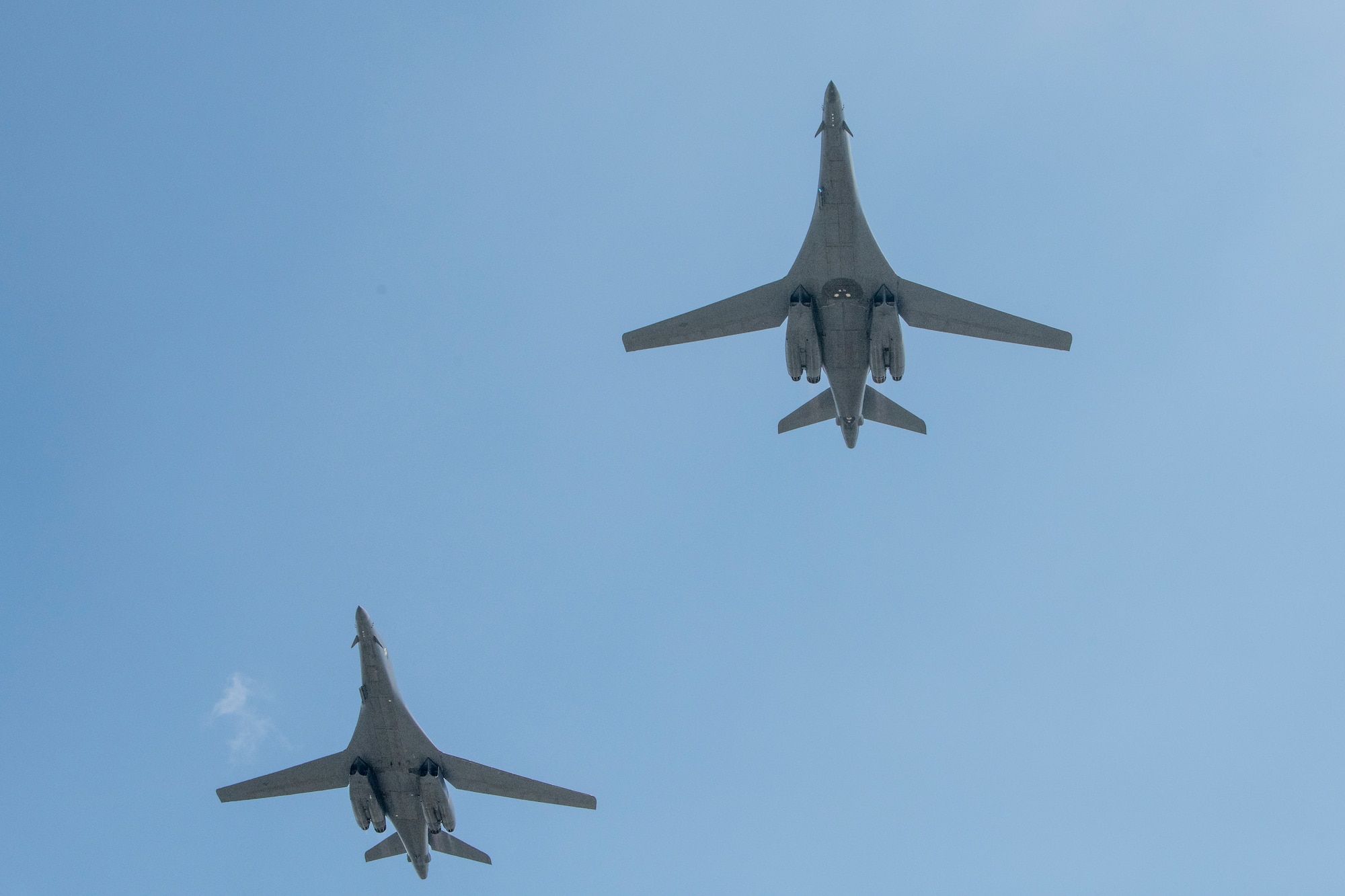 The undersides of two gray aircraft appear in a blue sky background.