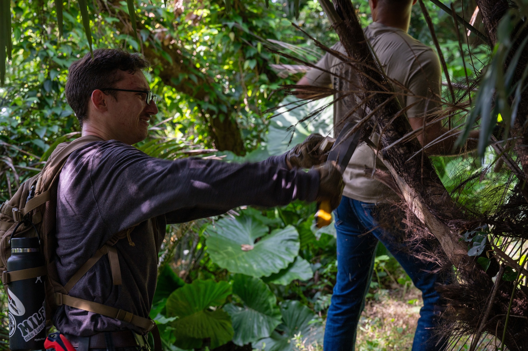 An airman cutting down a branch