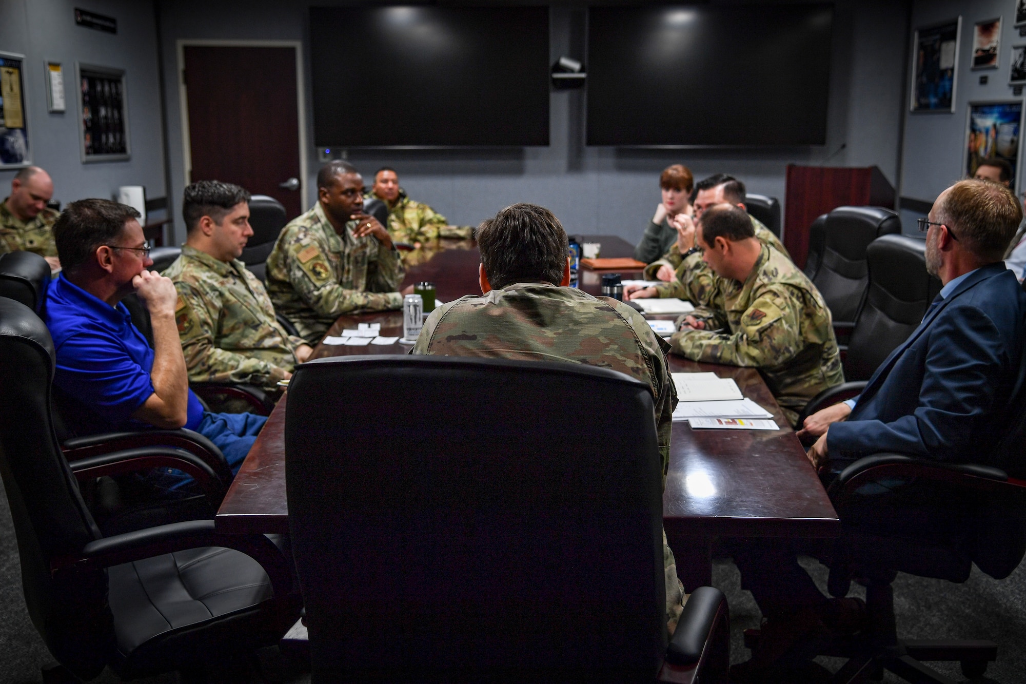 Air Force military members and civilians discuss information at a conference table.