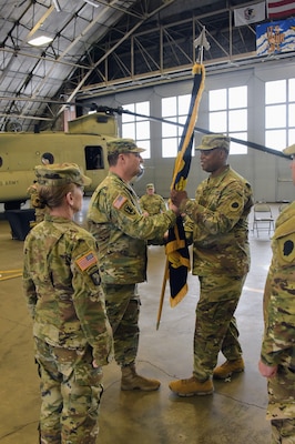 Col. Max Casteleyn, Commander of the 65th Troop Command Brigade, passes the brigade’s colors to Command Sgt. Maj. LaCarl Baker