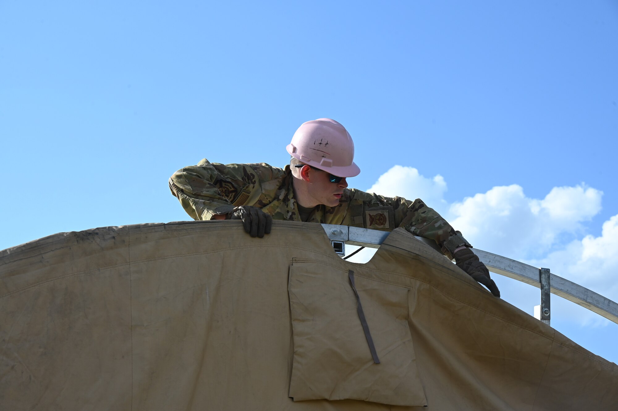 Maryland Air National Guard Senior Airman Eric Helmenstine, 175th Wing fire protection services, helps construct a small shelter system at the 145th Regional Training Site in Badin, North Carolina, April 4, 2025.