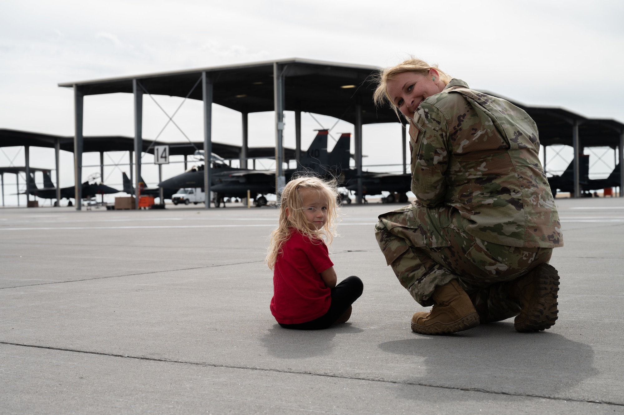 Senior non-commissioned officer sits alongside flightline with child