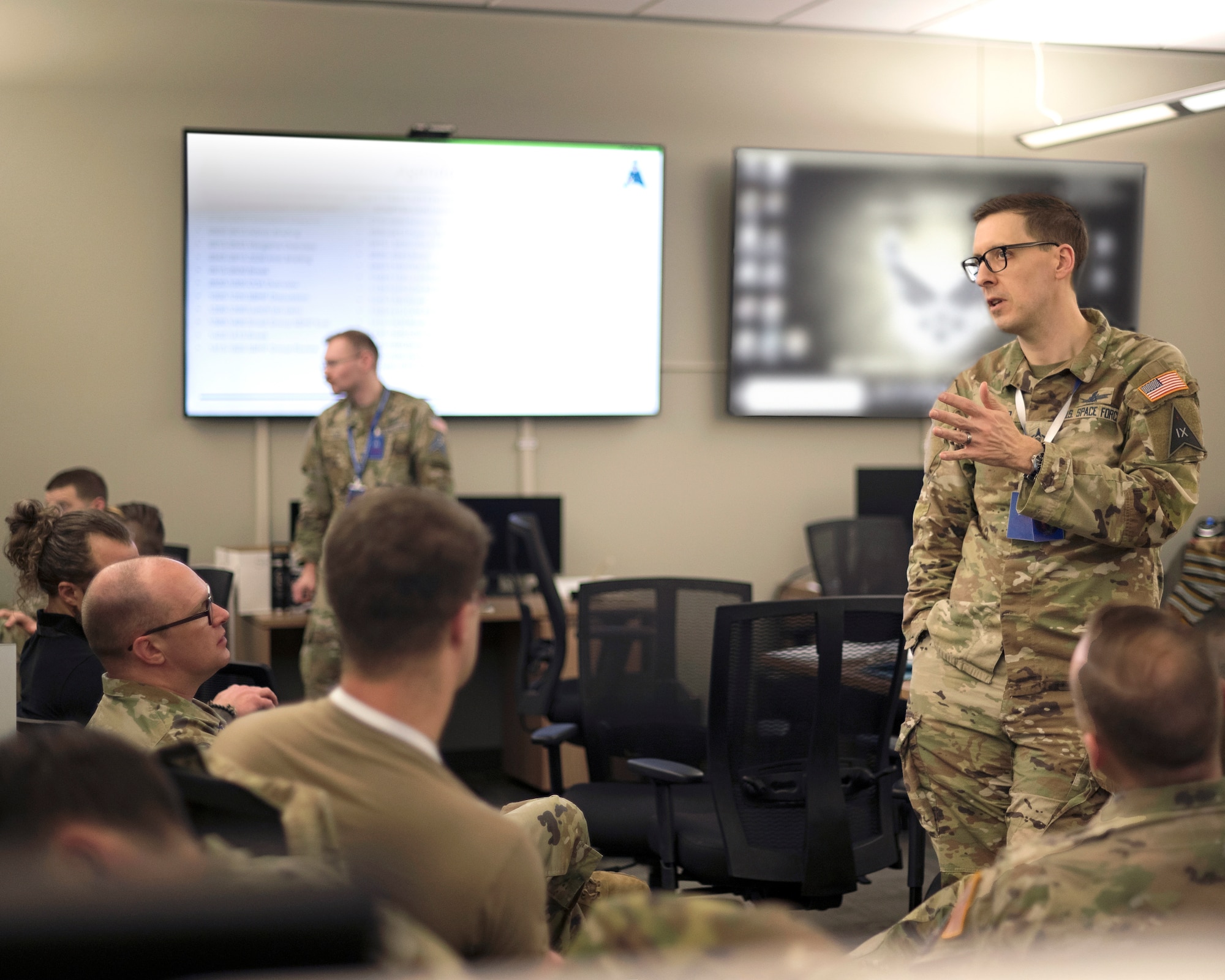 Man speaking to group in an office setting. All in uniform.