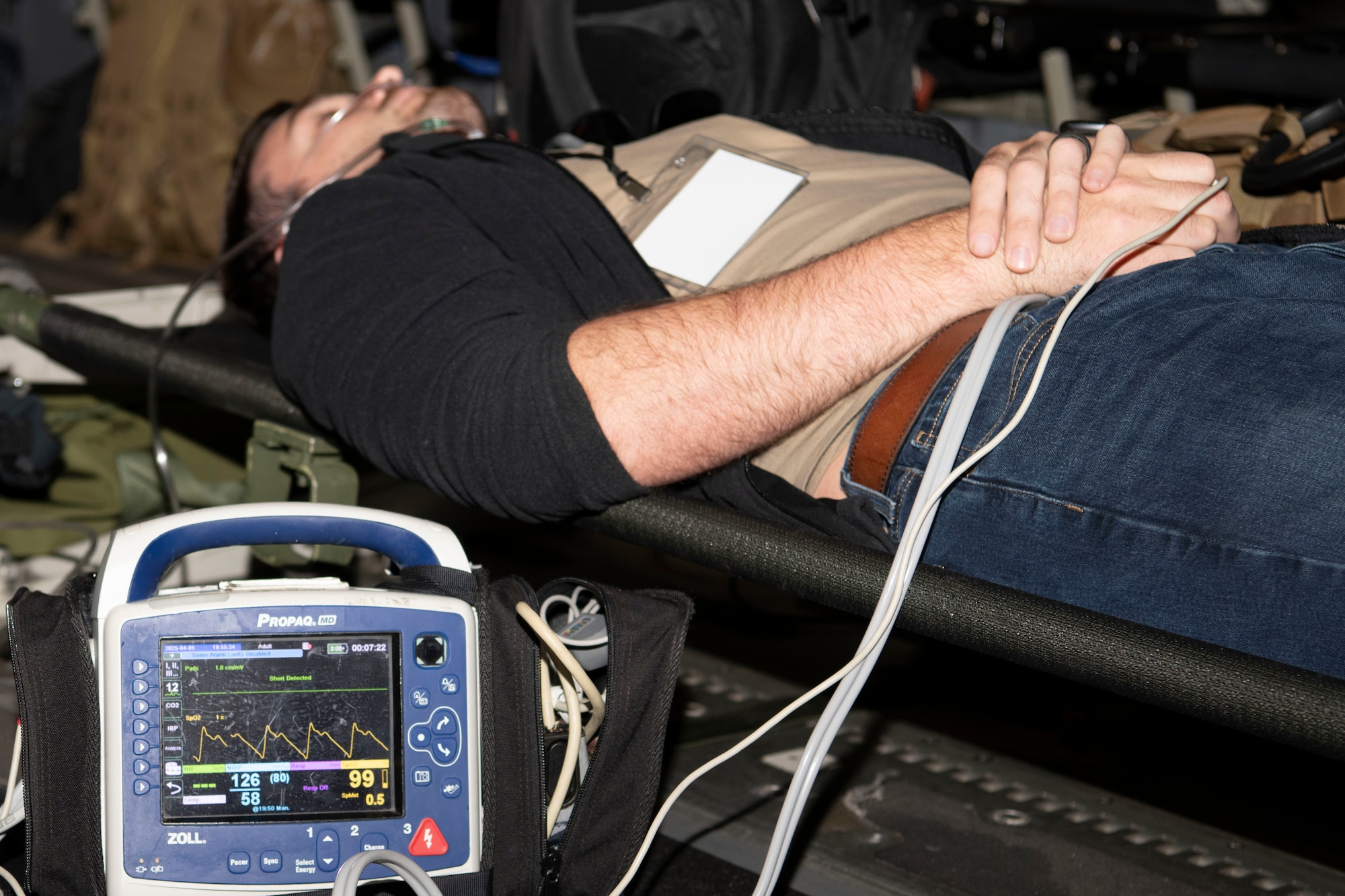 A spouse aboard the flight laying down on the table receiving medical care.