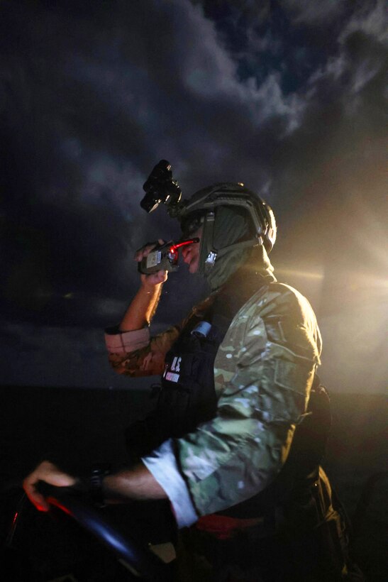 A Coast Guardsman in tactical gear in the dark.
