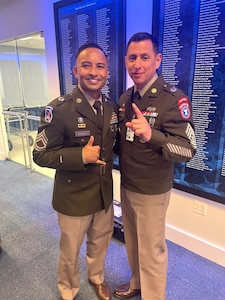 Two male Soldiers pose for a picture in dress uniform.