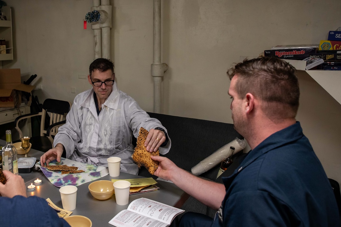two men seated at table break matzo