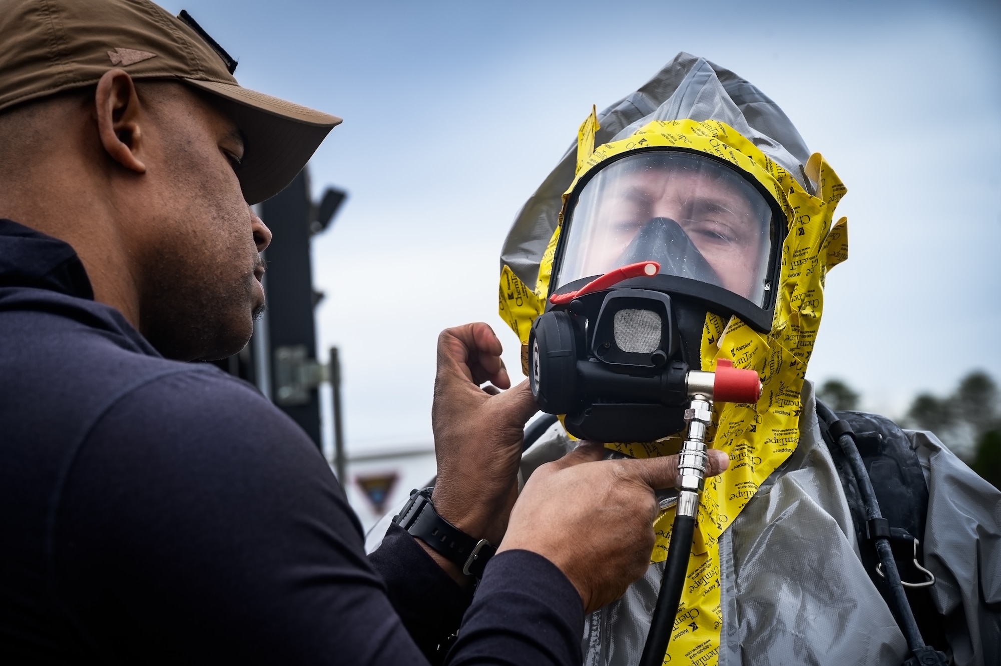 Trevor Donnatien and Ryan Petrovic, recitation response escorts assigned to the U.S. Army’s 20th Chemical, Biological, Radiological, Nuclear, Explosives (CBRNE) Analytical and Remediation Activity (CARA), test the seal on a hazardous materials respirator mask at Joint Base McGuire-Dix-Lakehurst, N.J., April 14, 2025. The CARA recitation response team was tasked to remove an unexploded MK II 75mm projectile with potential chemical components that was discovered at JB MDL. (U.S. Air Force photo by Senior Airman Matt Porter)