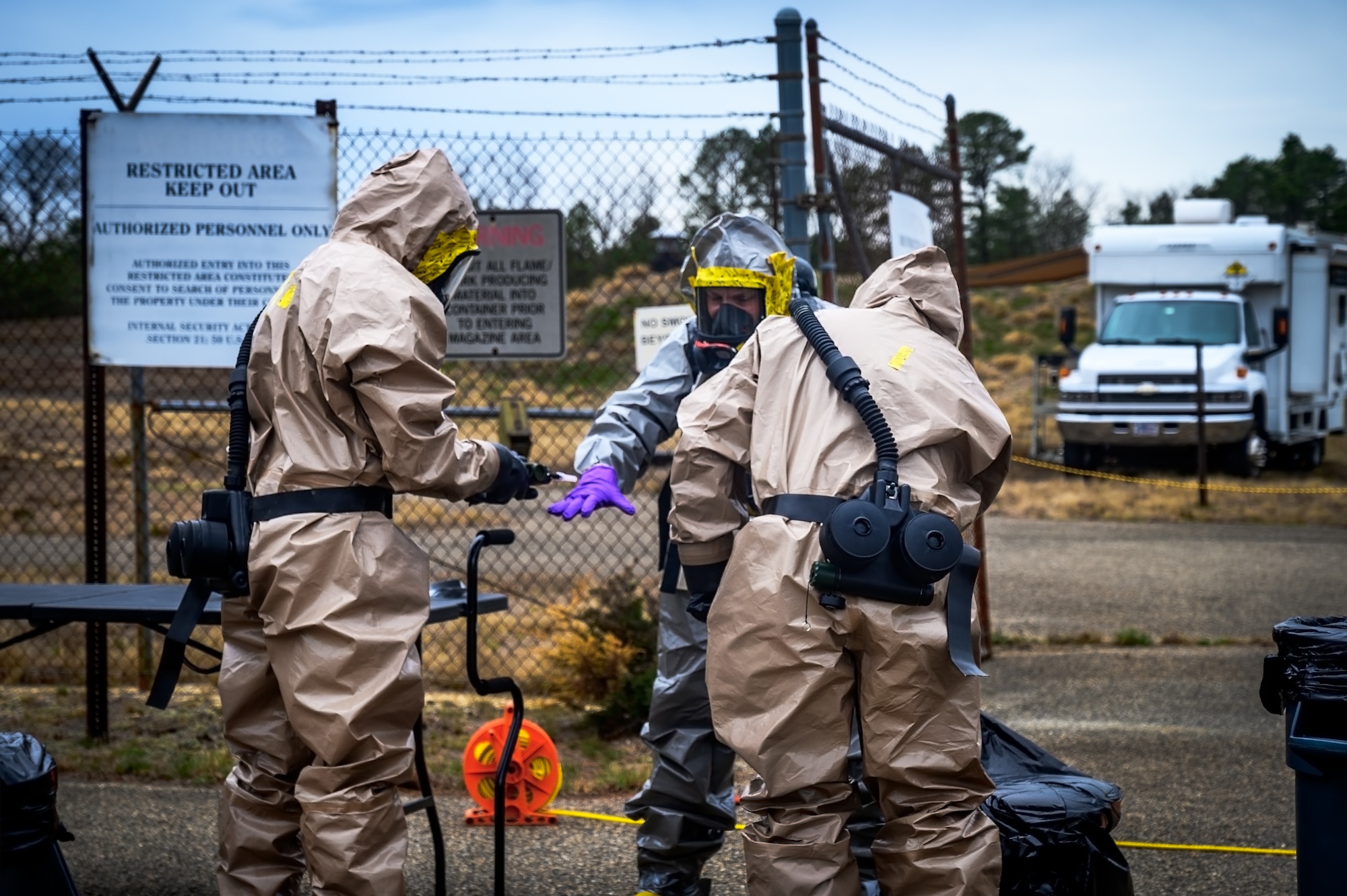 Ryan Petrovic (center), recitation response escort assigned to the U.S. Army’s 20th Chemical, Biological, Radiological, Nuclear, Explosives (CBRNE) Analytical and Remediation Activity (CARA), is checked for chemical exposure by U.S. Air Force Airmen assigned to the 87th Air Base Wing emergency management office at Joint Base McGuire-Dix-Lakehurst, N.J., April 14, 2025. The CARA recitation response team was tasked to remove an unexploded MK II 75mm projectile with potential chemical components that was discovered at JB MDL. (U.S. Air Force photo by Senior Airman Matt Porter)