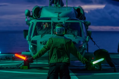 CORAL SEA (April 11, 2025) – Aviation Electronics Technician 3rd Class Trevor Bailey, from Post Fall, Idaho, assigned to the “Golden Falcons” of Helicopter Sea Combat Squadron (HSC) 12 communicates with the pilots of an MH-60S Seahawk helicopter...