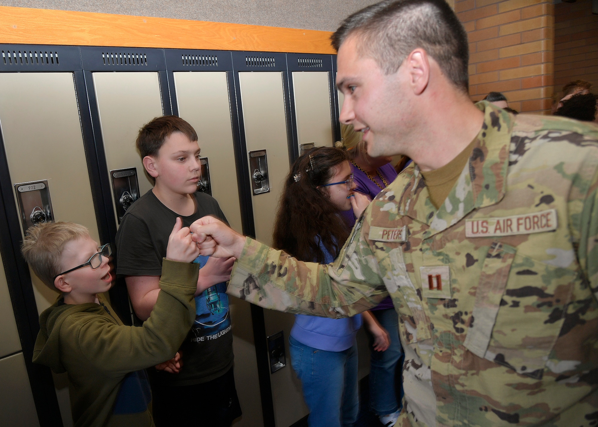 (Right) Capt. Aaron Peters, 75th Civil Engineer Squadron, fist-bumps junior high school students during a military parade April 11, 2025, at Syracuse Junior High School in Syracuse, Utah. Active-duty military from Hill Air Force Base and local veterans participated in the parade, which aimed to celebrate military families during Month of the Military Child in April. (U.S. Air Force photo by Todd Cromar)