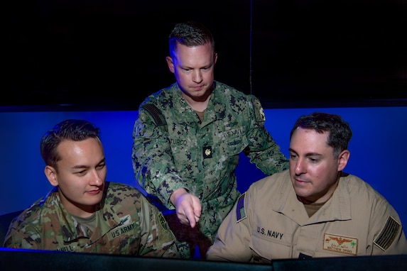 three uniformed members looking at computer screen