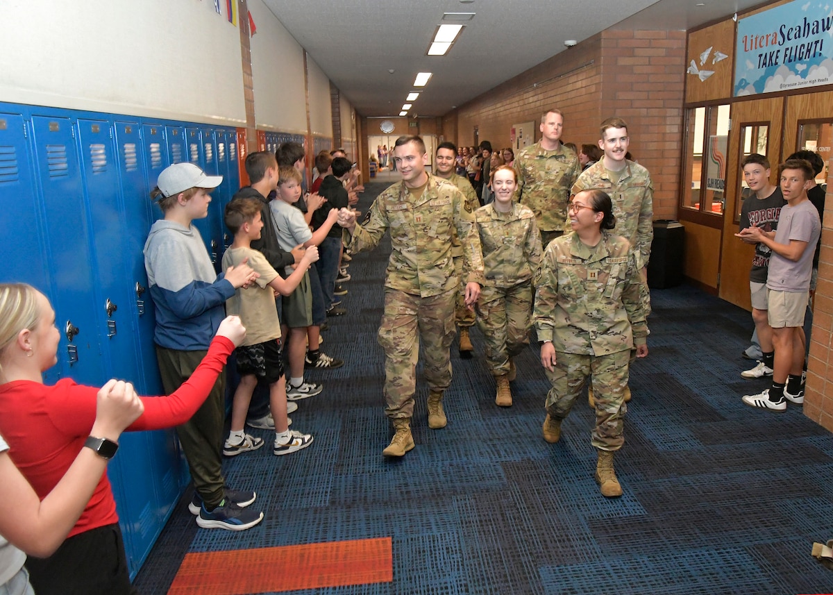 (Center) Capt. Aaron Peters, 75th Civil Engineer Squadron, fist-bumps students during a military parade April 11, 2025, at Syracuse Junior High School in Syracuse, Utah. Active-duty military from Hill Air Force Base and local veterans participated in the parade, which aimed to celebrate military families during Month of the Military Child in April. (U.S. Air Force photo by Todd Cromar)
