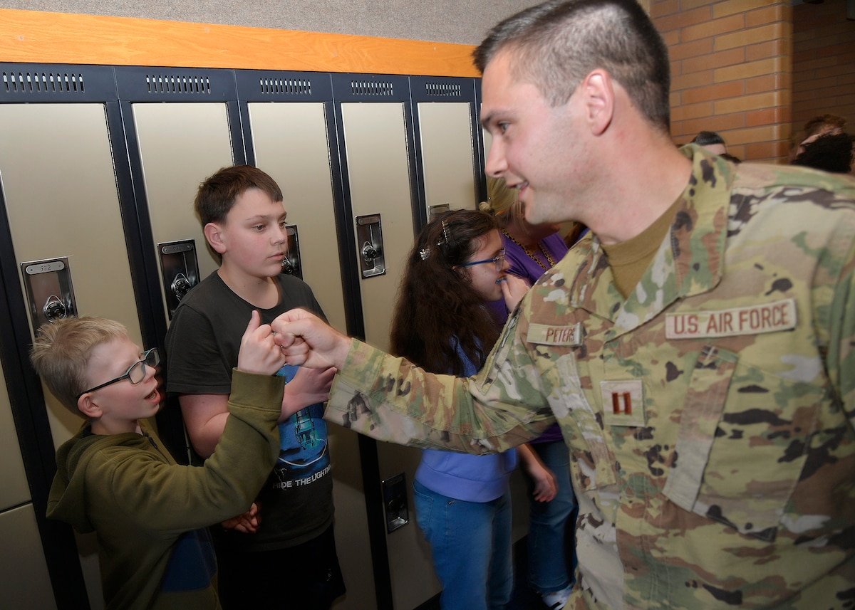 (Right) Capt. Aaron Peters, 75th Civil Engineer Squadron, fist-bumps junior high school students during a military parade April 11, 2025, at Syracuse Junior High School in Syracuse, Utah. Active-duty military from Hill Air Force Base and local veterans participated in the parade, which aimed to celebrate military families during Month of the Military Child in April. (U.S. Air Force photo by Todd Cromar)