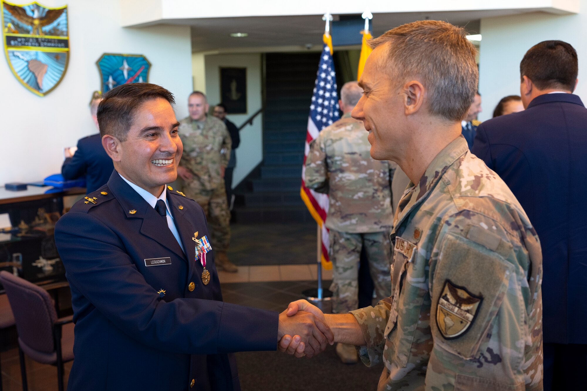 Colombian Air Force Col. Alejandro Leguizamón, Air Forces Southern foreign liaison officer, left, shakes hands with U.S. Air Force Maj. William Toronto, chief of operations and international law, right, after a medal presentation ceremony at Davis-Monthan Air Force Base, Arizona, March 25, 2025. Foreign liaison officers serve as vital conduits between partner nations and U.S. military organizations, helping foster trust, enhance interoperability and coordinate joint efforts in pursuit of shared defense goals. (U.S. Air Force Photo by Tech. Sgt. Rachel Maxwell)