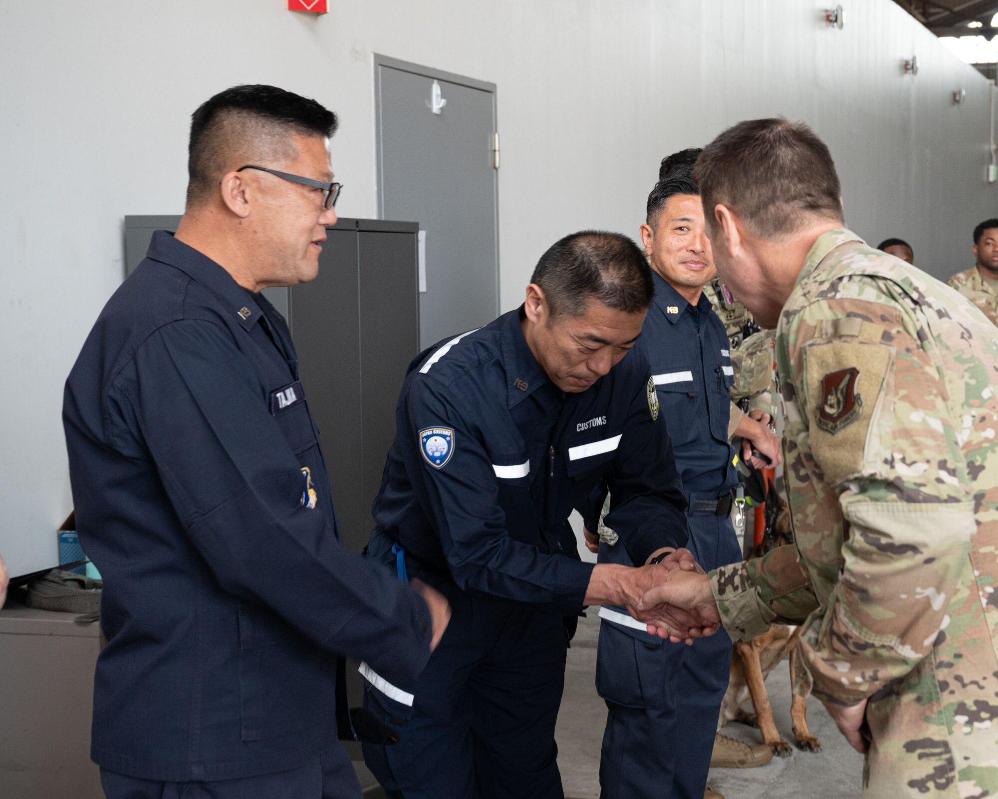 Uniformed Japanese personnel greet a U.S. service member