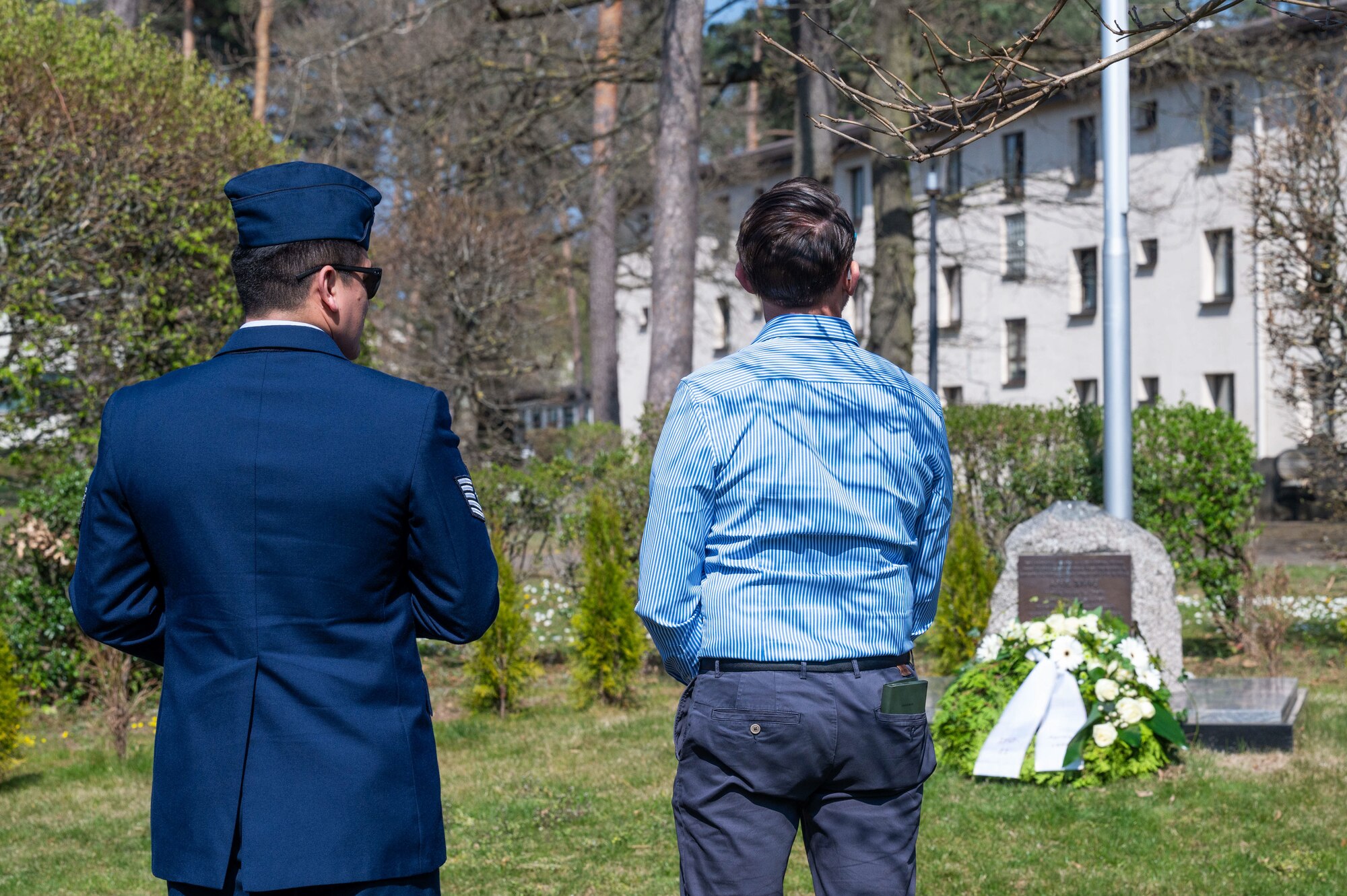 U.S. Airmen and civilians, belonging to the 76th Airlift Squadron, pay their respects at the Implementation Force-21 Memorial at Ramstein Air Base, Germany, April 10, 2025. The IFO-21 Memorial previously was placed outside the 76 AS building, but is currently situated outside the United States Air Forces in Europe and Air Forces Africa Headquarters.
