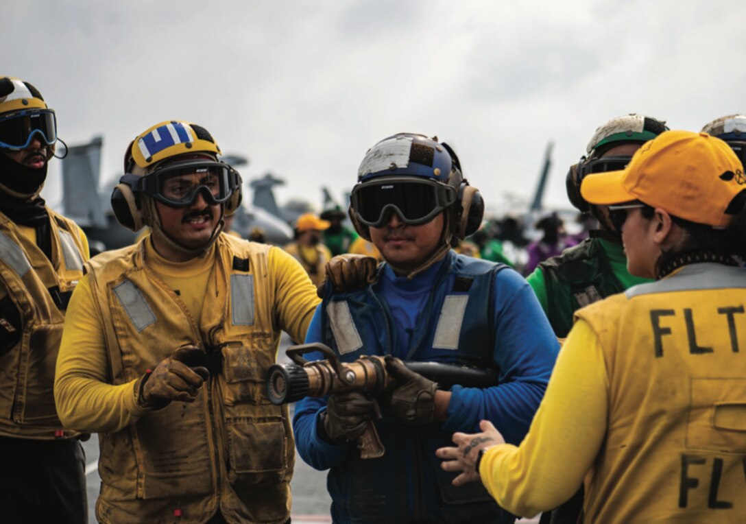 Three sailors participate in mass casualty drill on flight deck of aircraft carrier USS Nimitz, South China Sea.