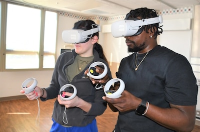 Womack Medical Simulator Operations Specialist, Don-Emeil Watson (R) guides Womack Nurse Lt. Gabrielle Meyo through a VR scenario on March 26, 2025.